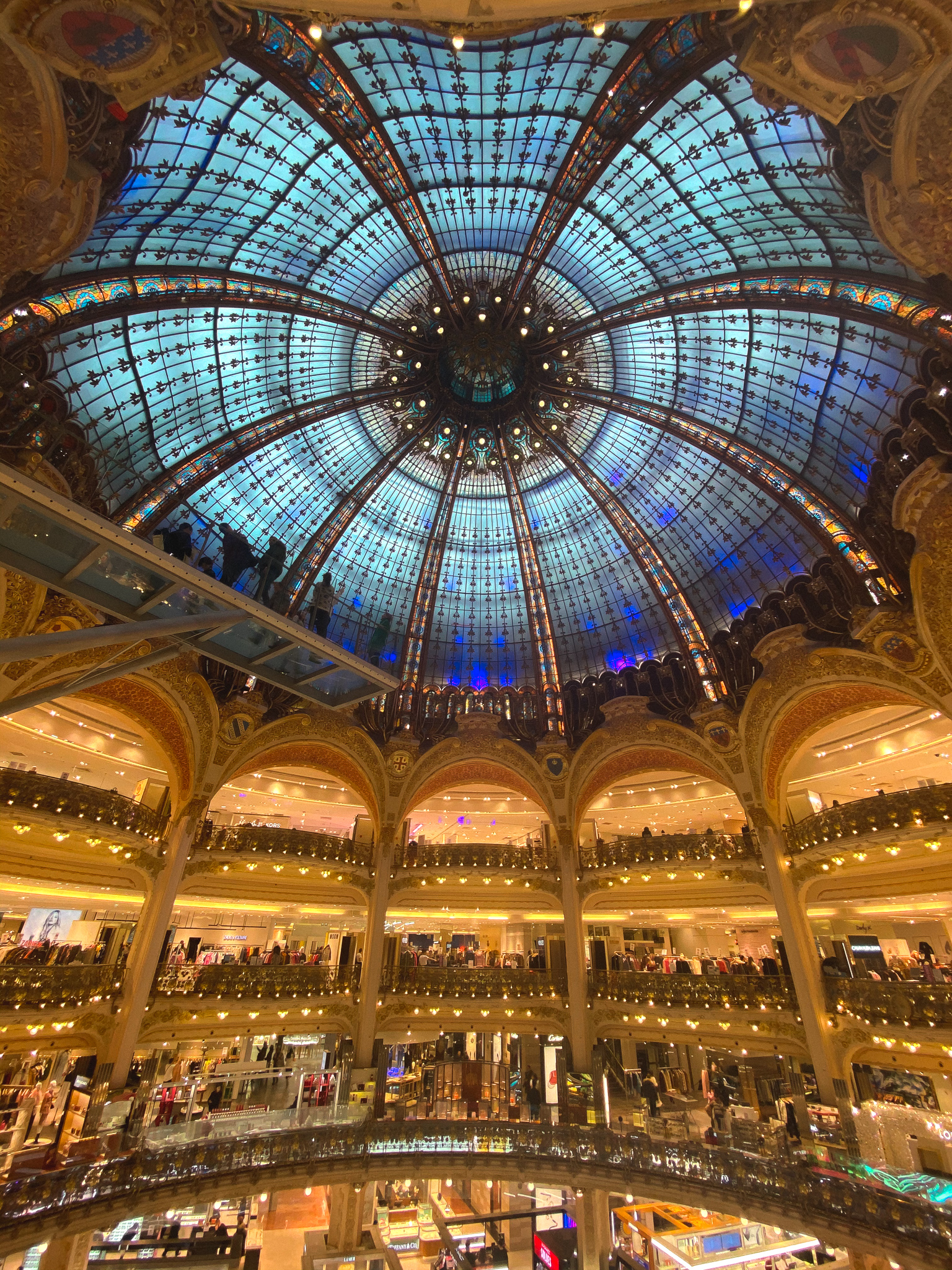Opulent interior of a grand shopping arcade with a magnificent stained glass dome, ornate balconies, and an impressive media management header.